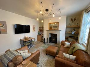 sala de estar con sofás, TV y chimenea en Apple Street Cottage, en Oxenhope