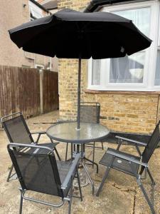 une table avec deux chaises et un parasol dans l'établissement A beautiful ground-floor flat., à Londres