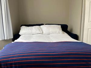 a bed with a blue and white blanket and a window at A beautiful ground-floor flat. in London