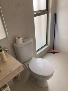 a bathroom with a white toilet and a window at Private room with air conditioning with private but non-attached bathroom Near airport in Devanahalli-Bangalore