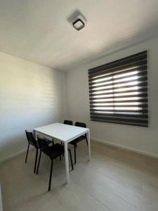 - une table et des chaises blanches dans une chambre avec fenêtre dans l'établissement Apartamento Luda, à Torreperogil