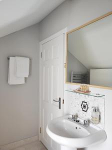 ein weißes Badezimmer mit einem Waschbecken und einem Spiegel in der Unterkunft Portrush by the Sea - 6 Golf Terrace in Portrush