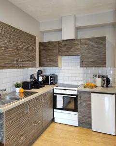 cocina con armarios de madera y horno de fogón blanco en Portrush by the Sea - 6 Golf Terrace, en Portrush