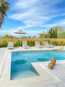 una piscina con sedie e ombrelloni di My Corfu Luxury Villa with private pool at Sidari a Sidari