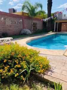a swimming pool with flowers in front of a house at La Palmera in Deán Funes
