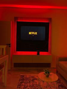 una televisione in un soggiorno con illuminazione rossa di ThePlaceForYou Central Apt a Shkodër