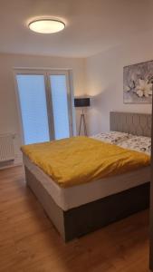 a bedroom with a bed with a yellow blanket on it at komfortná novostavba v centre in Poprad
