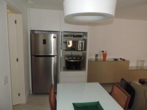 a kitchen with a table and a stainless steel refrigerator at Ocean Flat in Rio de Janeiro
