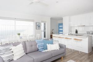 a living room with a couch and a kitchen at Sea Poppy in Casuarina