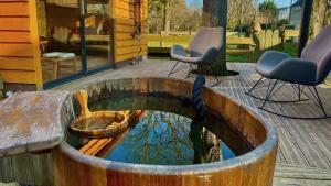 a wooden barrel with a bird bath and chairs on a deck at Spa de campagne Ressource gite THALASSO privatisée INCLUS in Dormelles