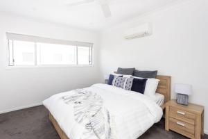 a white bedroom with a bed and a window at Sea Poppy in Casuarina