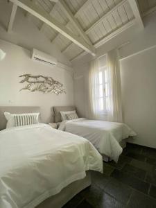 a white bedroom with two beds and a window at Spetses Cozy Villa in Spetses