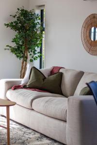 a white couch in a living room with a tree at Riccarton 2 bed 1 bath w/garage in Christchurch