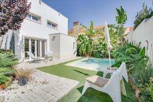 a backyard with a pool with a chair and an umbrella at White and Light House in Costa da Caparica