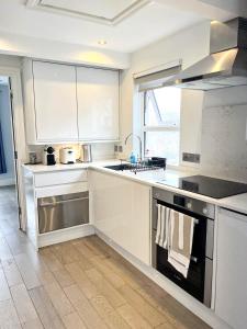 cocina blanca con fregadero y fogones en Modern 1 Bedroom flat close to Vauxhall en Londres