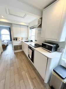 a kitchen with white cabinets and a counter top at Modern 1 Bedroom flat close to Vauxhall in London