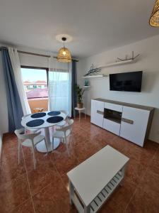 a living room with a table and a tv at BAHIA AZUL in Caleta De Fuste