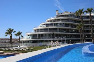 a large white building with a swimming pool in front of it at Luxury Apartment Infinity View in Arenales del Sol