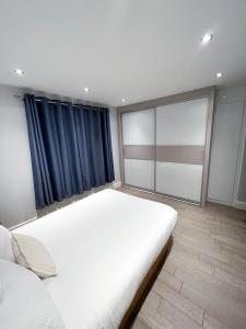 a bedroom with a large white bed and blue curtains at Modern 1 Bedroom flat close to Vauxhall in London