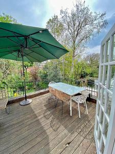 a table and chairs with a green umbrella on a deck at Amazing holidays home with a terrace in London