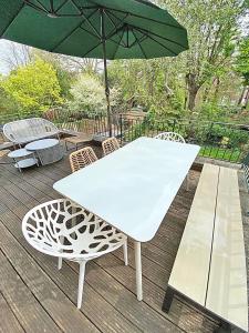 a white table and chairs with an umbrella on a deck at Amazing holidays home with a terrace in London