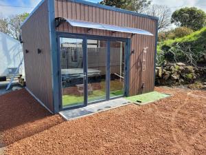a small shed with a door and windows at Tranquil 2 Bedroom Cottage With Hot Tub Sea View Teach Cha in Sessiagh