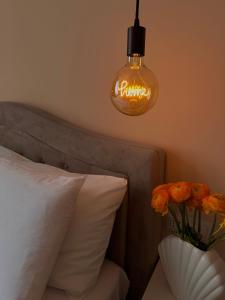 una luz colgando sobre una cama con un jarrón de flores naranjas en Rhospitality - Visconti Affittacamere, en Rho