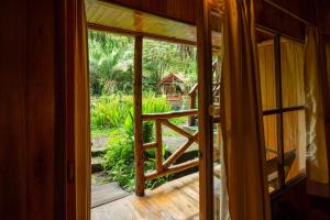 een open deur naar een veranda met uitzicht op een tuin bij Mindo Lago Hotel Destino in Mindo