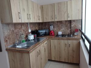 una pequeña cocina con armarios de madera y fregadero en Apartamento ideal si buscas ubicación y espacio, en Pereira