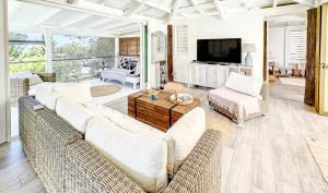 a living room with white furniture and a television at Villa Cazou, sea view, private pool, Wifi 100Mbps in Oyster Pond