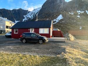 un'auto parcheggiata in un parcheggio di fronte a una casa di Reinefjord panorama a Moskenes
