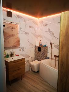 ein Badezimmer mit einer Badewanne, einem WC und einem Waschbecken in der Unterkunft Apartament Sfera in Bielsko-Biała