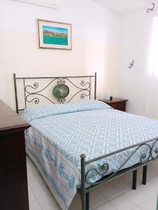 a bedroom with a bed with a blue and white comforter at Villa Milena Villasimius, WiFi gratuito, Ampio Giardino a 300 m dal Mare in Villasimius