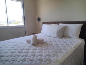 uma cama branca com duas toalhas em cima em AP Moderno em Pelotas
