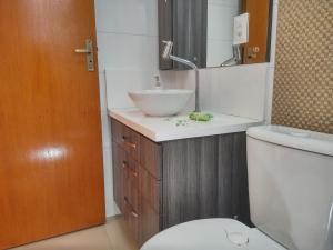 a bathroom with a sink and a toilet and a mirror at AP Moderno in Pelotas +28 photos