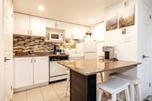 a kitchen with white cabinets and a counter with stools at Mountainside Studio Bliss Pool, Hot Tubs, At the Mountain in Blue Mountains