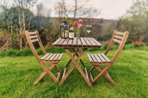 una mesa de picnic con 2 sillas, botellas de vino y flores en Luxury Glamping Cabin with Outdoor Bath on Cornish Flower Farm, en Truro