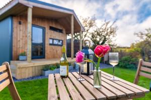 a wooden table with wine glasses and flowers on it at Luxury Glamping Cabin with Outdoor Bath on Cornish Flower Farm in Truro +37 photos