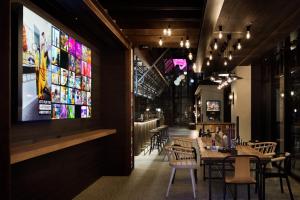 um restaurante com mesas e cadeiras e um grande ecrã em Moxy Osaka Shin Umeda em Osaka