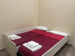 een bed met rode lakens en witte handdoeken bij Nonna Concetta B&B Nocera - Vicino Tribunale di Nocera - Ristrutturato 2022 in Nocera Inferiore
