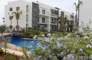 een gebouw met een zwembad en bloemen ervoor bij Perla Garden Bay in Casablanca