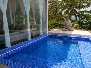 a buddha statue sitting next to a swimming pool at The Dream Beach Resort in Taytay