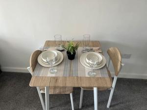 a wooden table with plates and wine glasses on it at City scenic view 1 Bedroom apt in Manchester
