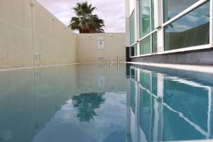 リヤドにあるホリデイ イン メイダンのヤシの木のある建物の隣の水のプール