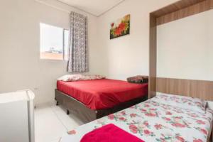 - une chambre avec 2 lits avec des draps rouges et une fenêtre dans l'établissement Pousada Casa da Fernanda, Suíte Sky, à Praia Grande