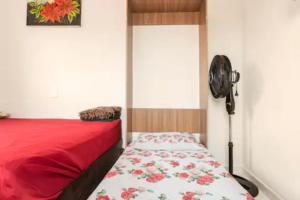 Schlafzimmer mit einem Bett mit einer roten Decke und einem Ventilator in der Unterkunft Pousada Casa da Fernanda, Suíte Sky in Praia Grande