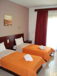 Cette chambre d'hôtel comprend 2 lits avec des draps orange et blancs. dans l'établissement Kourtis, à Paramythiá
