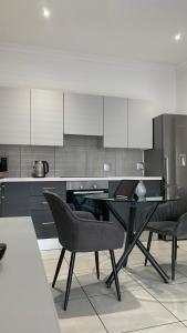 a kitchen with a table and chairs and white cabinets at CALDESMO - Upmarket Apartment in Pretoria