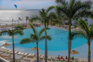 una piscina con palmeras y una playa en Suites @ Aria Ocean, en Nuevo Vallarta 