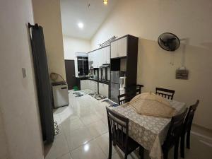 a kitchen and dining room with a table and chairs at Hakim Harmoni Homestay Air Hitam in Air Hitam